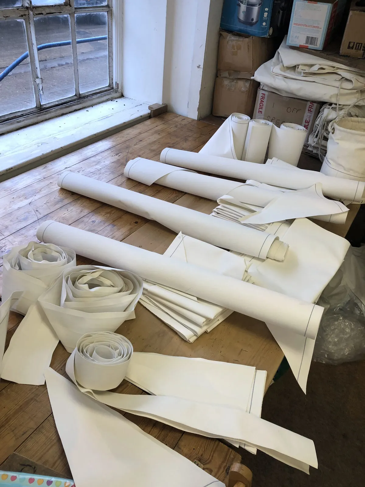 Rolls of white canvas on a workbench in the workshop today
