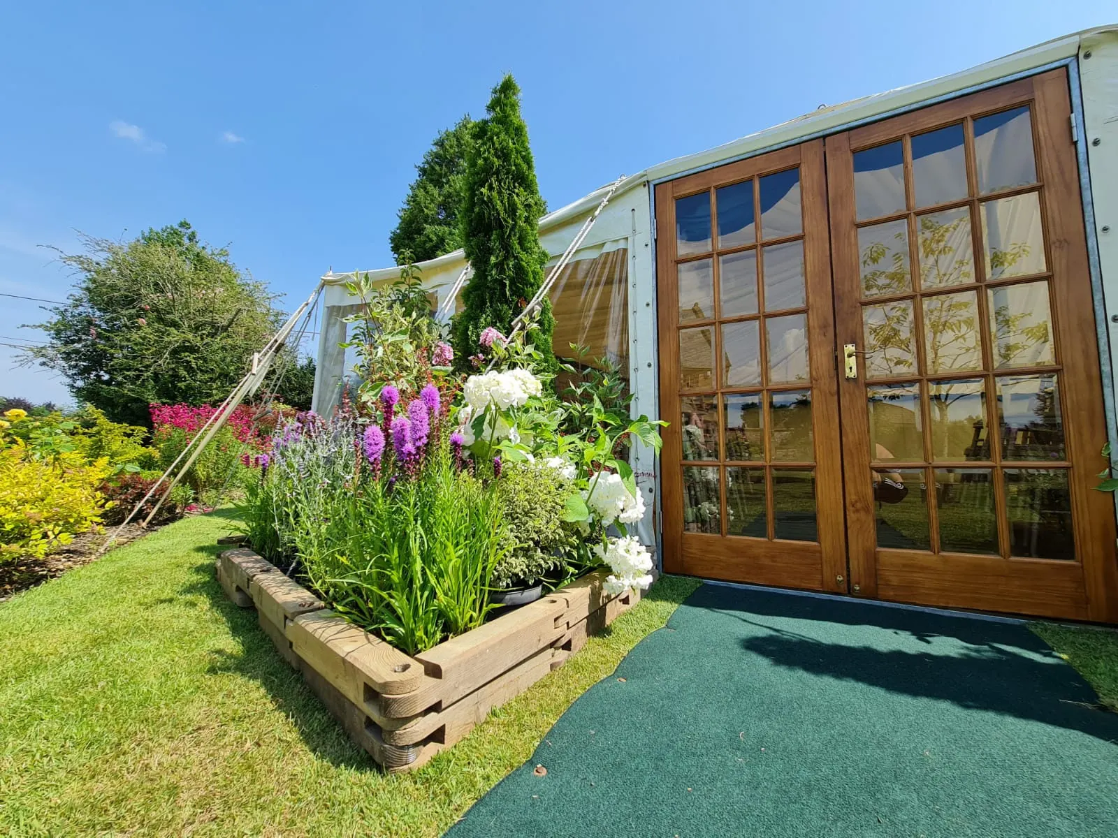 Glazed double doors at a marquee entrance, framed by flower planters
