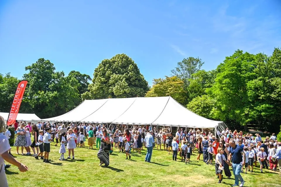 A crowd at an outdoor festival with large marquees
