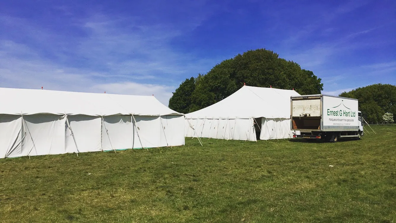 Marquees pitched in a field with the Ernest G. Hart van parked alongside