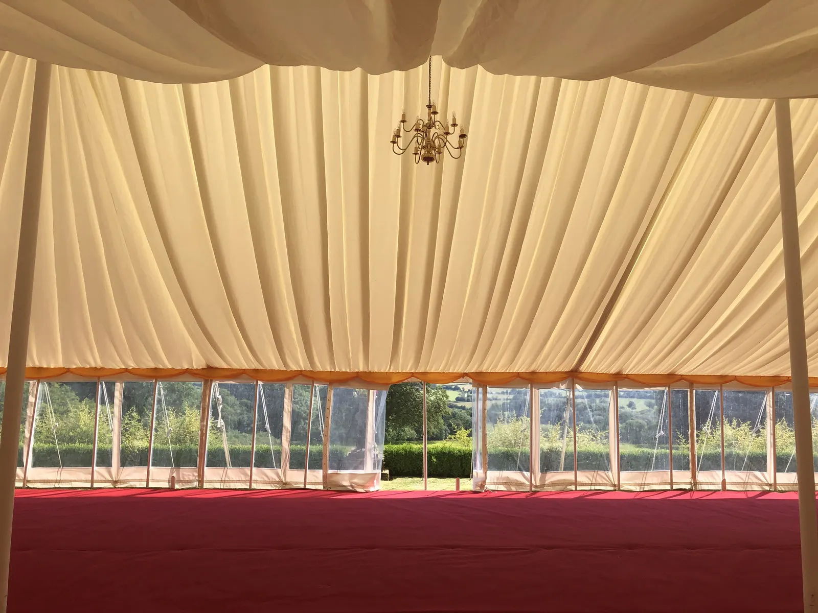 Red carpet flooring under a pleated marquee lining with chandeliers