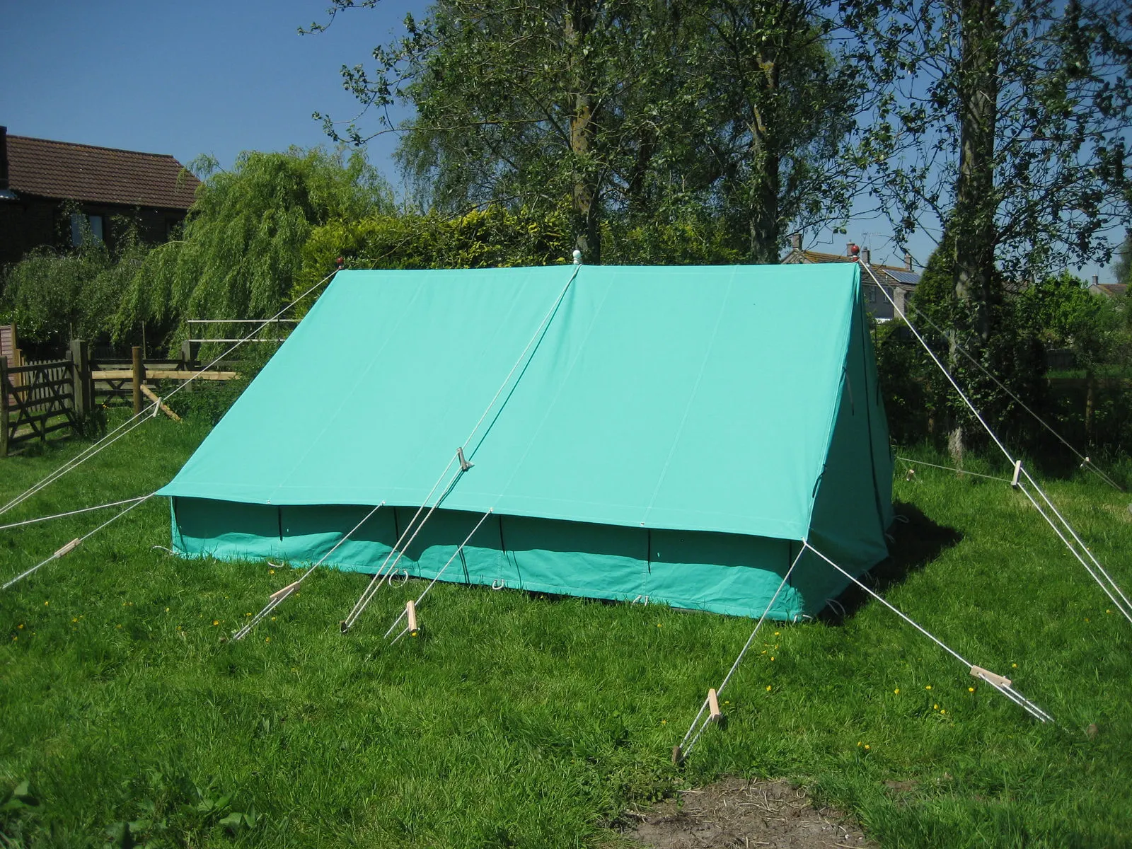 A green canvas ridge tent pitched on grass
