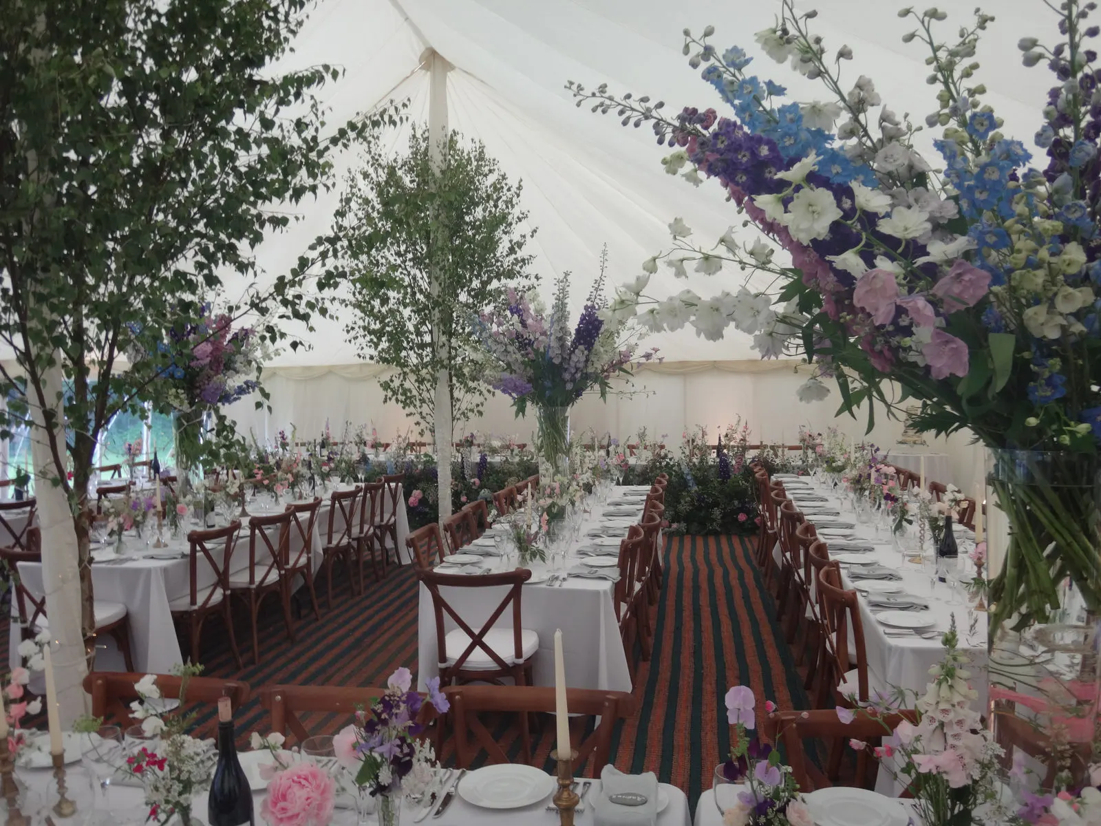 Long banquet tables dressed with wildflowers under a lined marquee